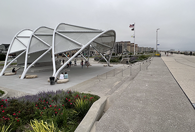 ROK-Amphitheater The amphitheater from the side, clearly showing its silver-metal three nested awnings that comprise the roof. To the right is the Rockaway Beach Boardwalk